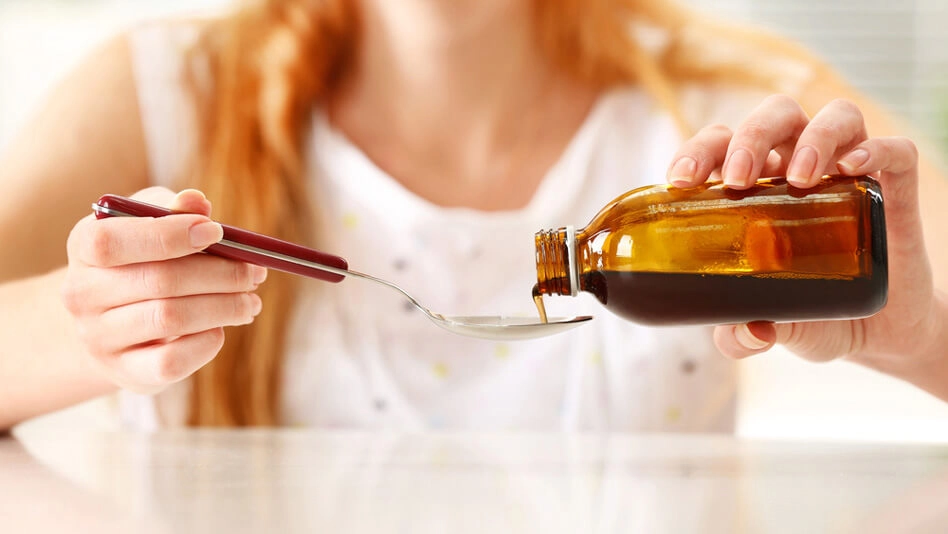 Woman pouring liquid medicine onto a spoon