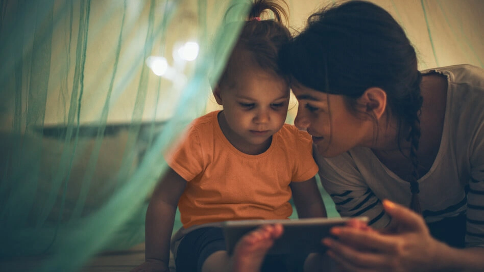 Young girl showing a tablet device to a toddler girl