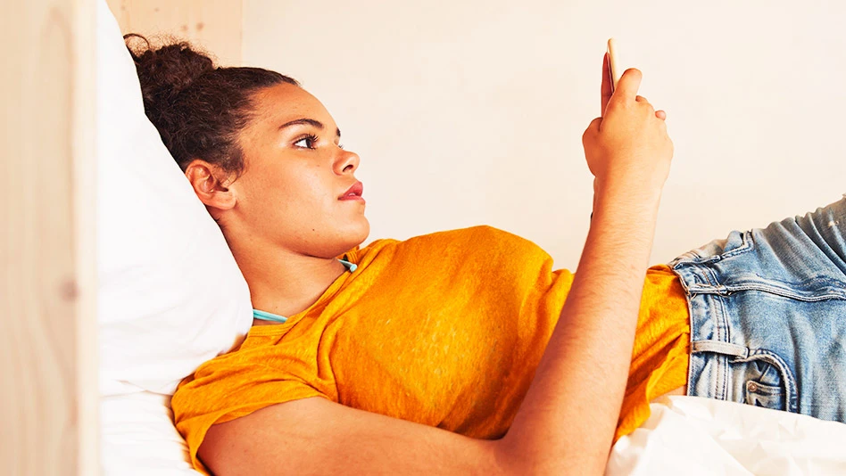 Woman laying in bed looking at her phone
